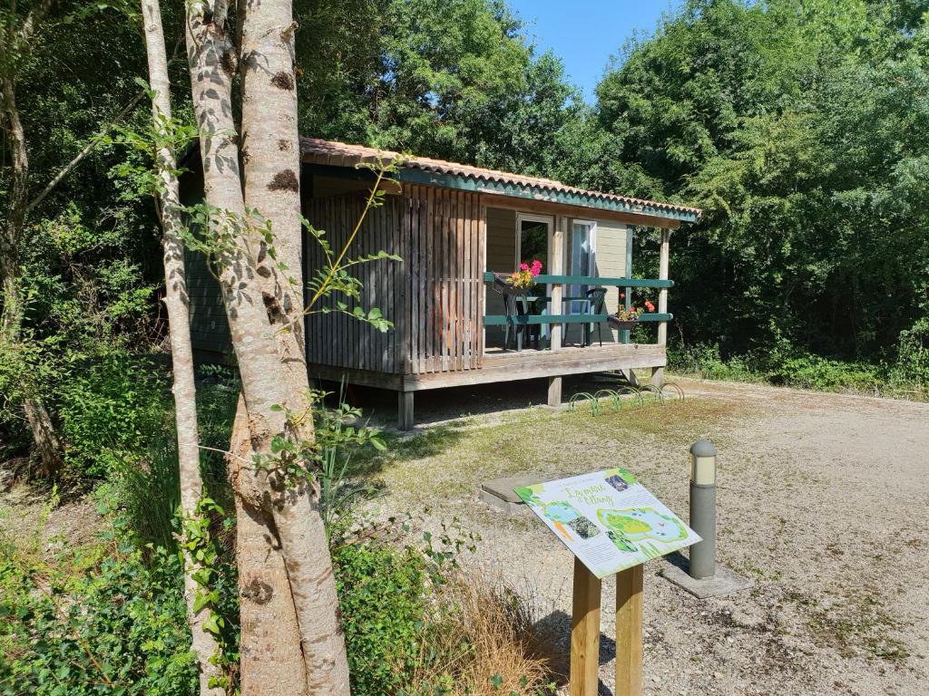 a small wooden cabin with a sign in front of it at Chalet de La Héronnière in Chef-Boutonne