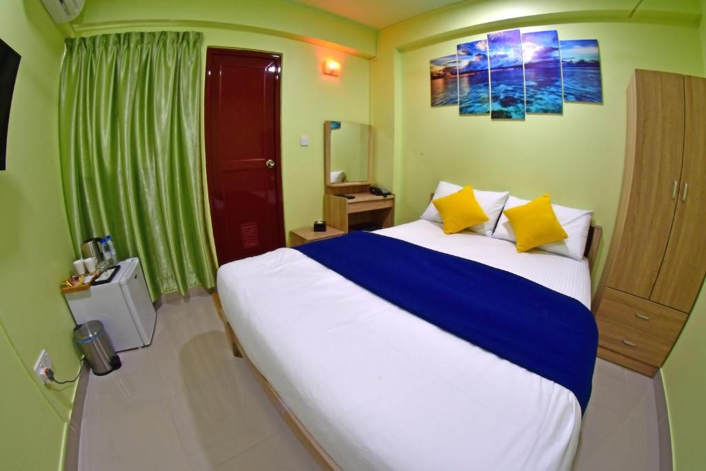 een slaapkamer met een groot bed met gele en blauwe kussens bij Tourist Inn in Male City