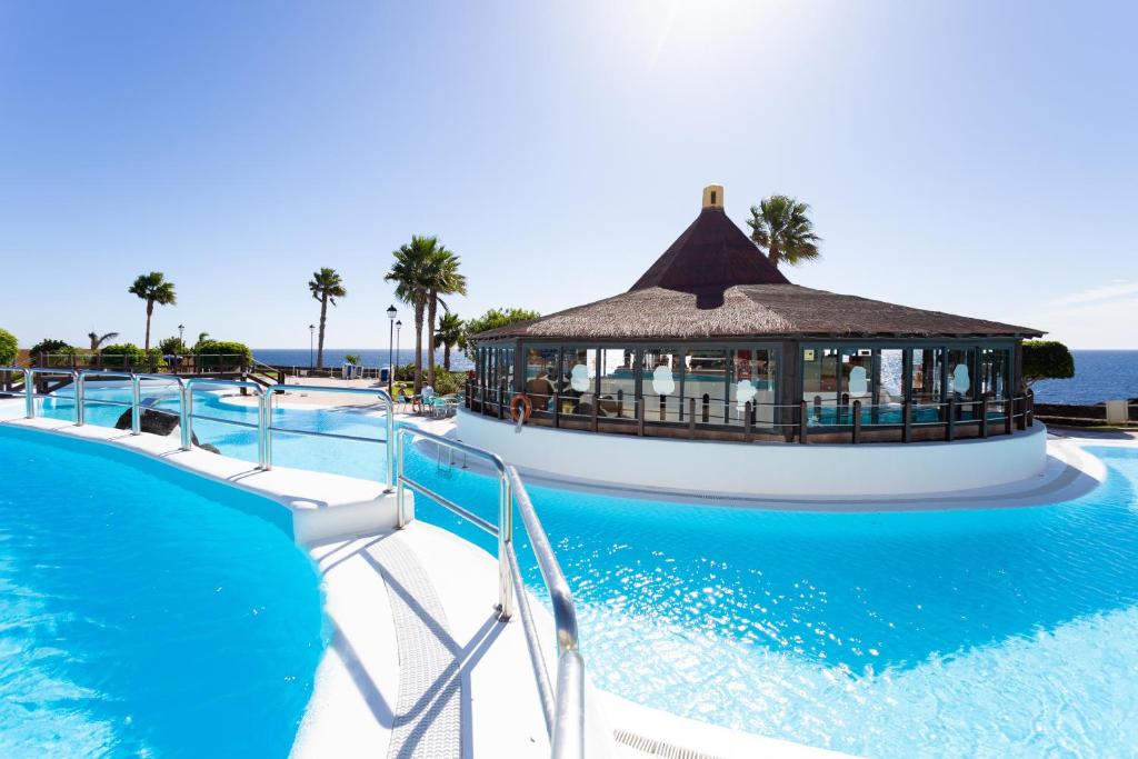 a resort swimming pool with a gazebo in the water at Rocas del Mar Apartment in Costa Del Silencio