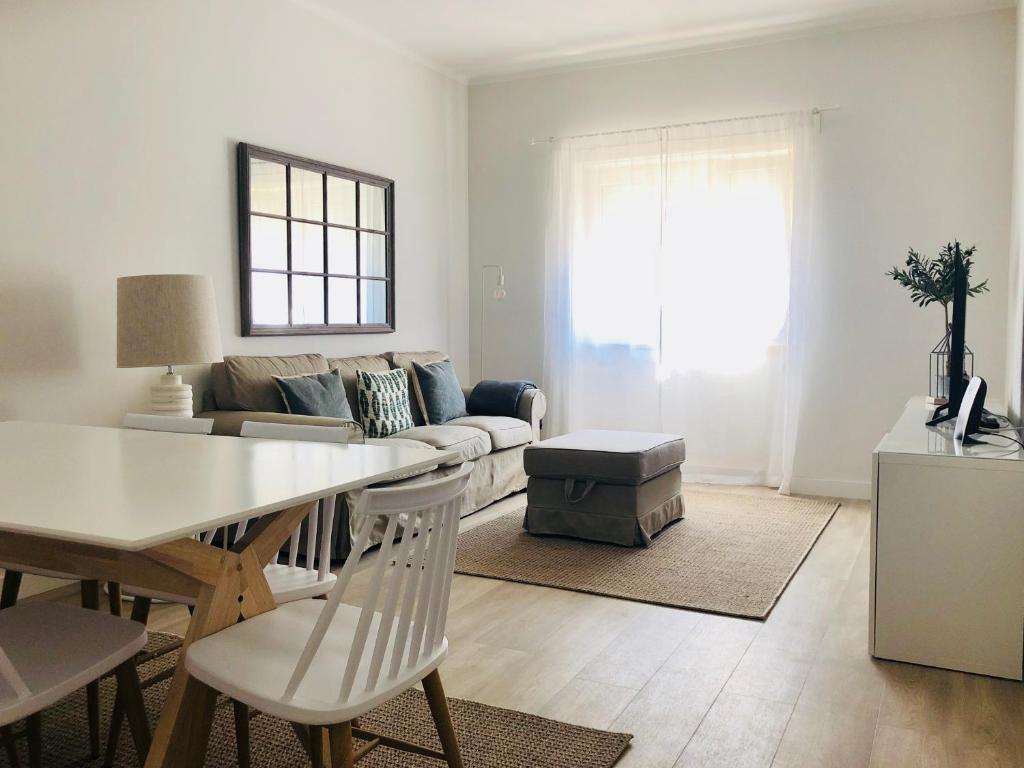 een woonkamer met een tafel en een bank bij Moderno apartamento, central e confortável in Montijo