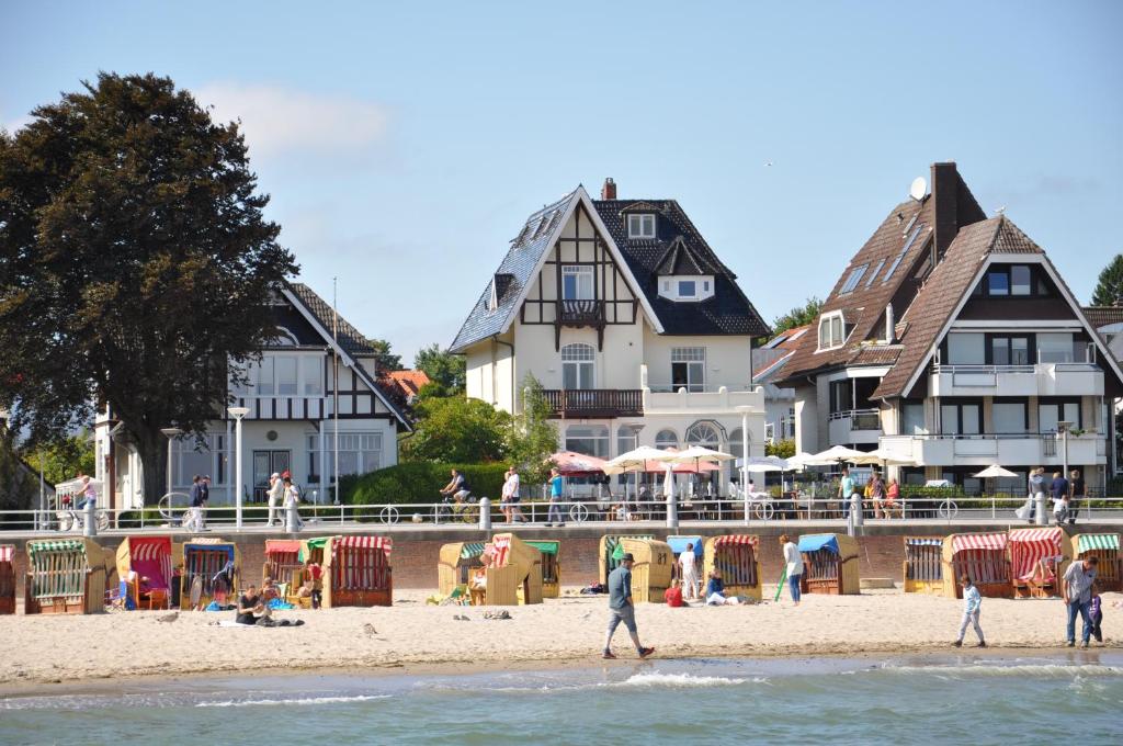 people walking on the beach in front of houses at Lieblingsplatz Hotel Strandperle in Travemünde