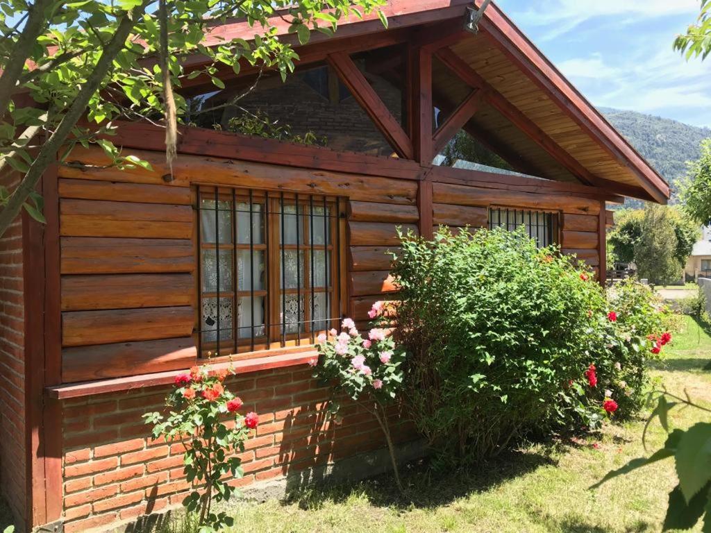 Cabaña de madera con ventana y arbusto en Cabañas del Alba en Lago Puelo