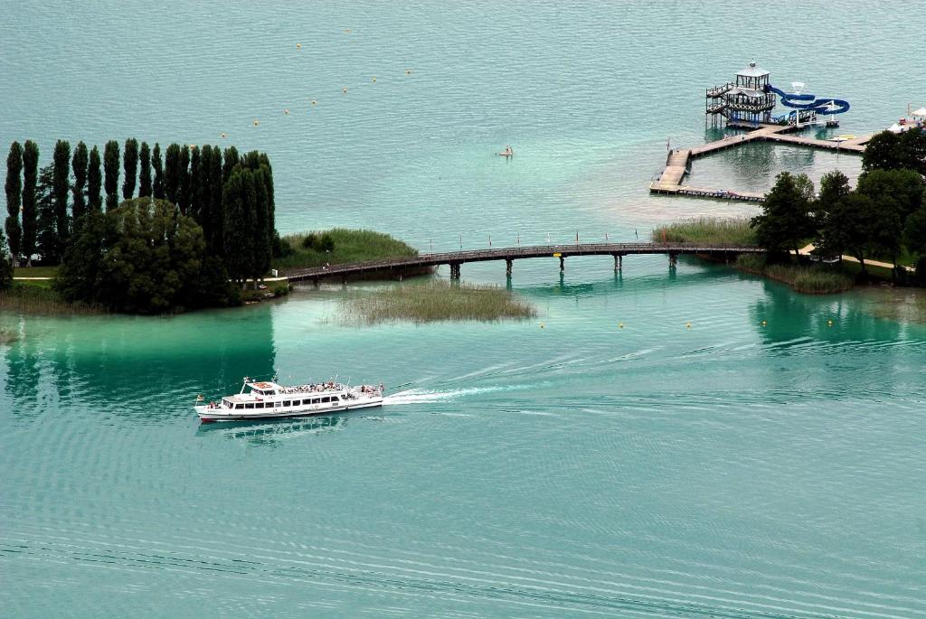 a boat in the water near a bridge at Apartements Kaschitz in Pörtschach am Wörthersee