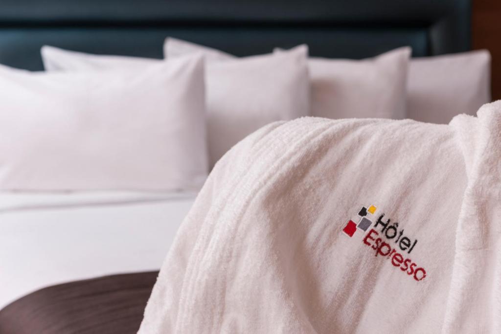 فندق اسبريسو مونتريال سنتر- فيل / داونتاون في مونتريال: سرير مع بطانيه بيضاء عليها لافته