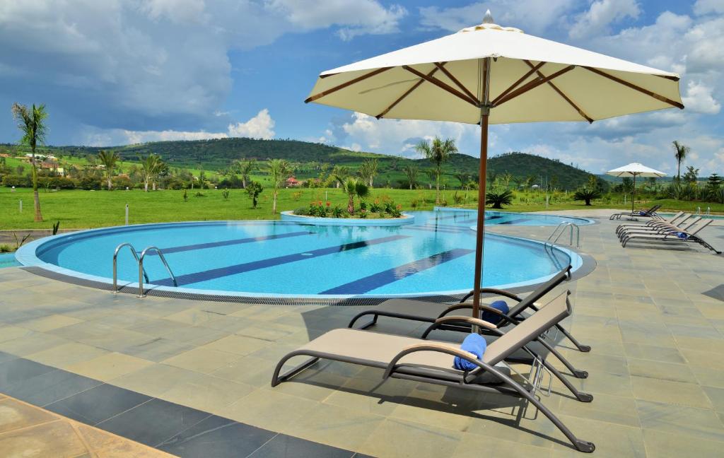 a swimming pool with chairs and an umbrella and an umbrella at EPIC Hotel & Suites in Nyagatare