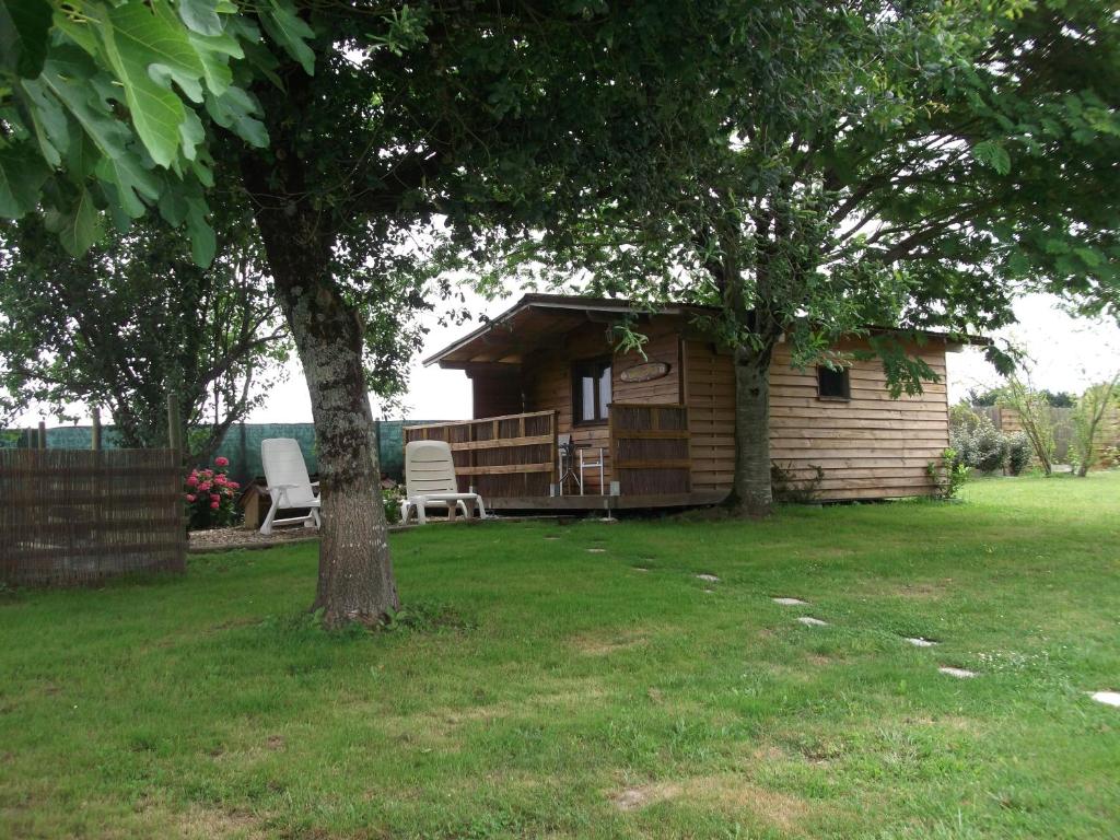 a log cabin with two chairs and a tree at Chalet La Forge De Clermont in Clermont