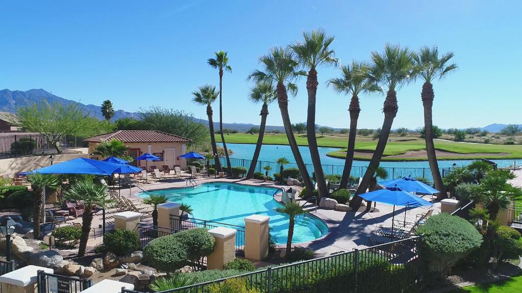 a pool with palm trees and blue umbrellas at Canoa Ranch Golf Resort in Green Valley
