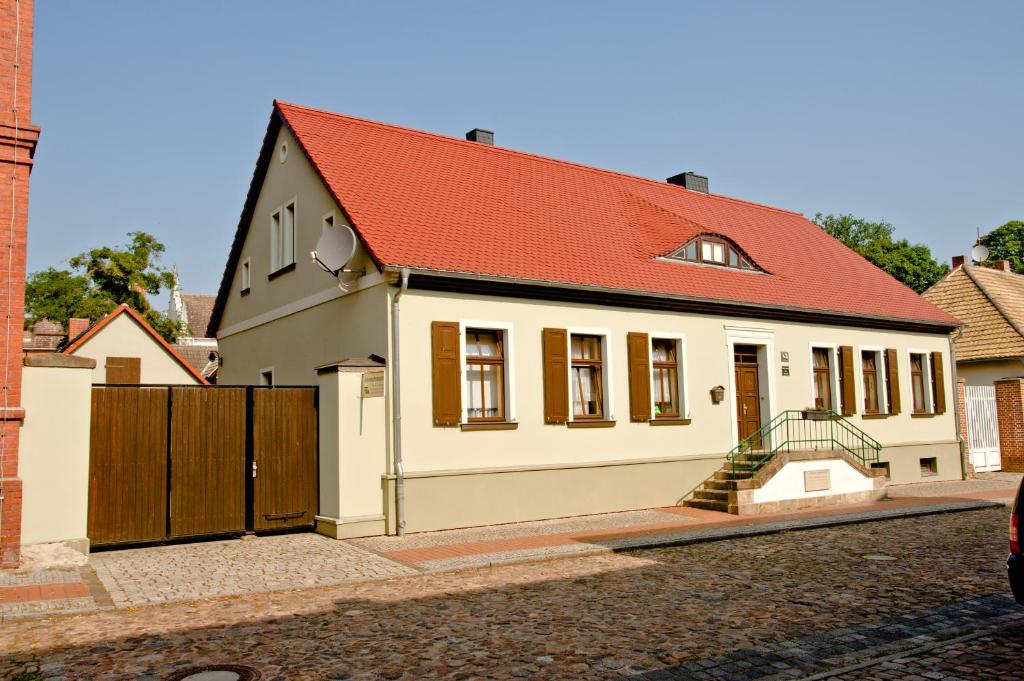 una pequeña casa blanca con techo rojo en Ferienwohnung Matthisson en Oranienbaum-Wörlitz