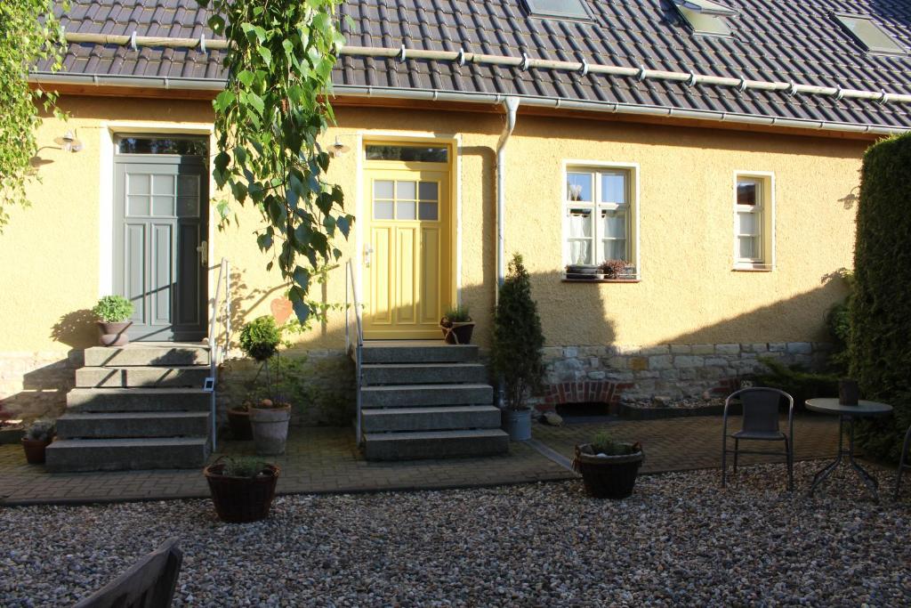 a yellow house with a yellow door and stairs at landhaus rosmarin in Oschersleben