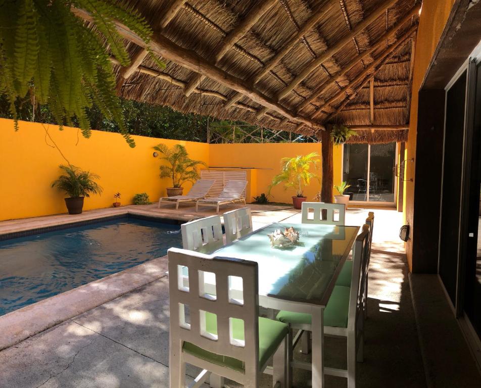 um pátio com uma mesa e cadeiras ao lado de uma piscina em ARRECIFES HOUSE 100 meters from the beach em Cancún
