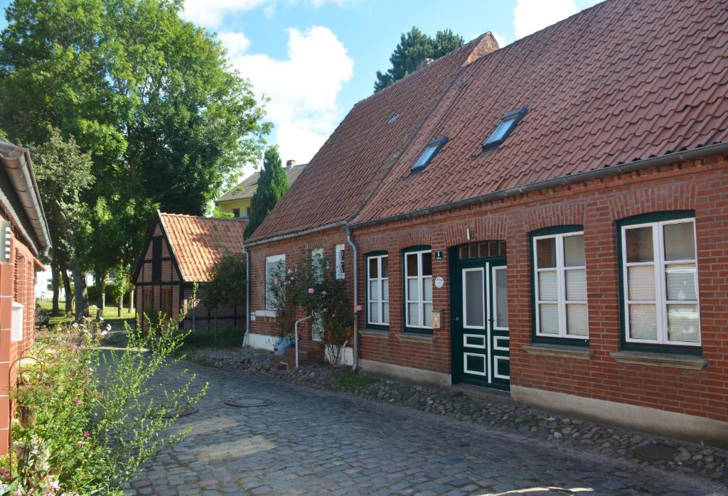 una casa de ladrillo con techo rojo y una calle adoquinada en Leuchtturm, en Fehmarn