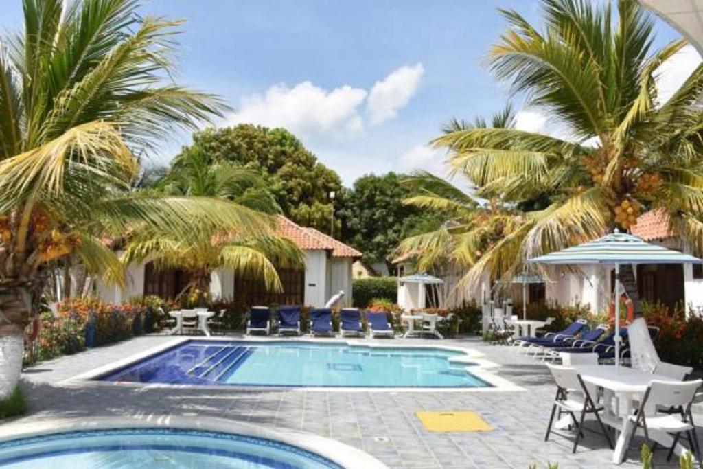 a pool with palm trees and chairs and a house at Condominio Atlantis in Coveñas