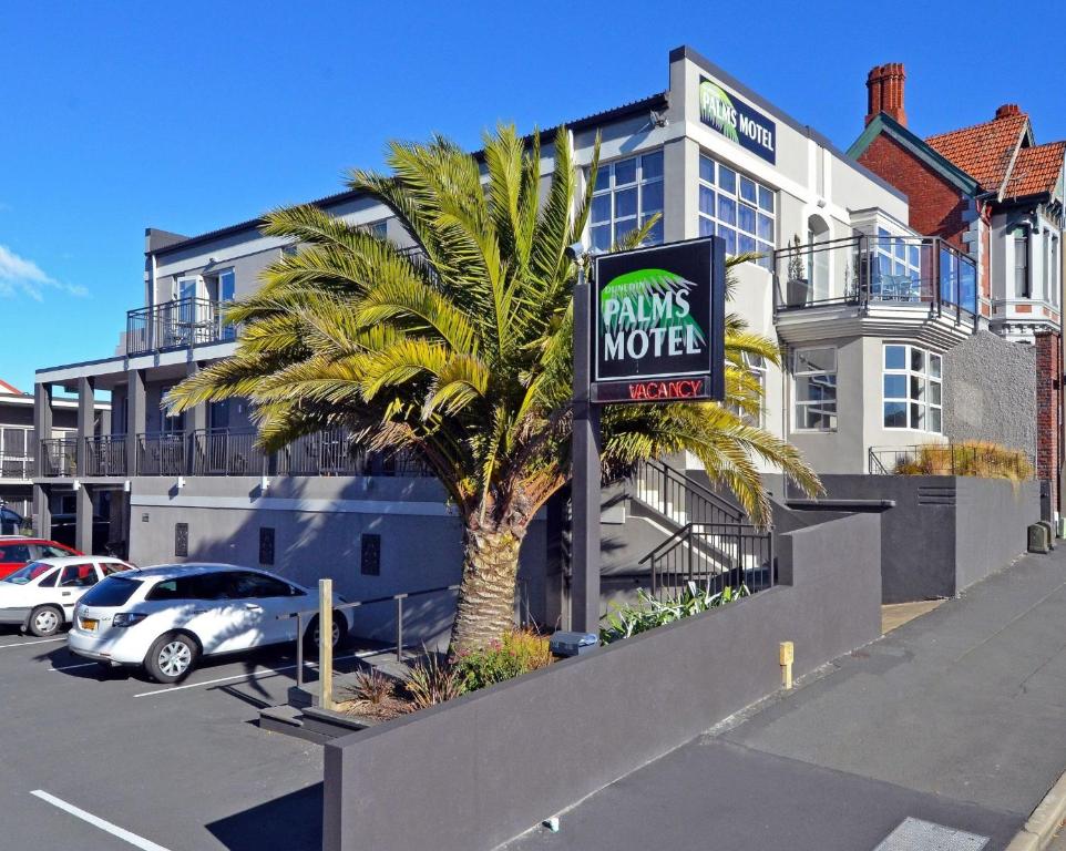 eine Palme vor einem Hotel mit einem Drink mehr Schild in der Unterkunft Dunedin Palms Motel in Dunedin