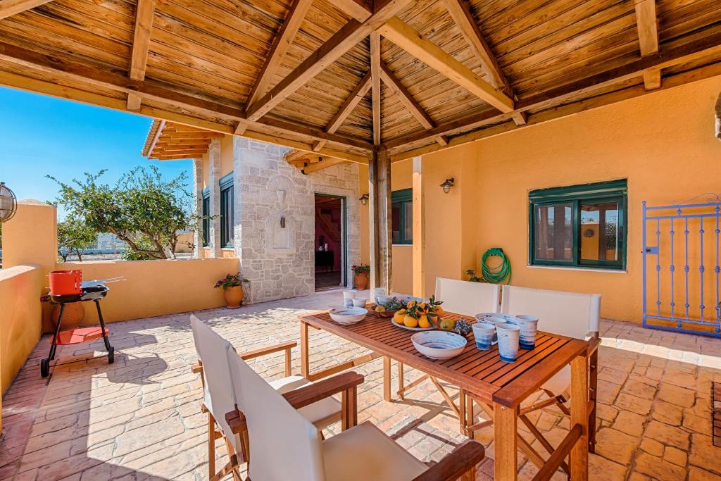 an outdoor patio with a wooden table and chairs at Eleftherias Garden House in Afantou