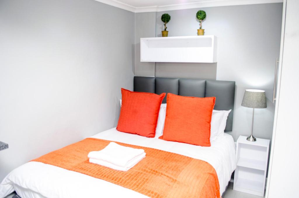 a bedroom with a large bed with orange pillows at Cape Town Micro Apartments in Cape Town