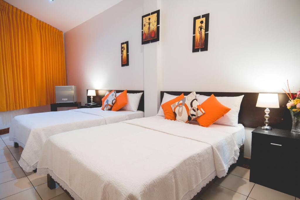 - 2 lits dans une chambre d'hôtel avec des oreillers orange dans l'établissement Hotel Fatima Inn, à Tarapoto