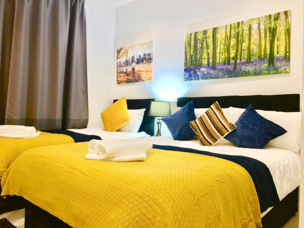 North WoolwichにあるLondon ExCel 2 Bedrooms River View Apartmentのベッドルーム1室(黄色と青の枕が備わるベッド2台付)