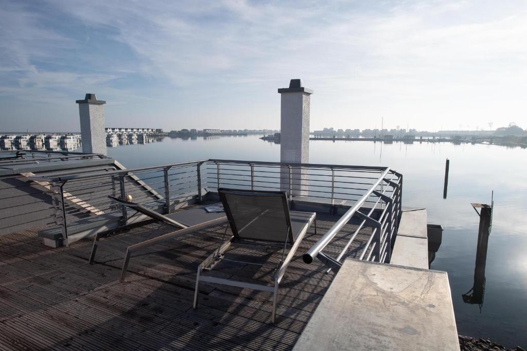 a dock with a table and a chair on the water at Haus Hafenblick in Olpenitz