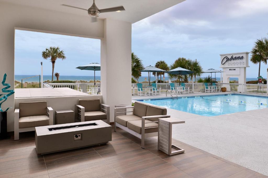 una piscina con sillas, una mesa y un edificio en Cabana Shores Hotel en Myrtle Beach