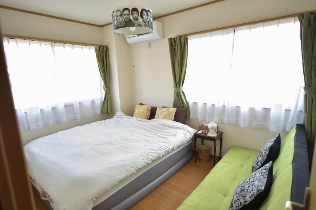a small bedroom with a bed and two windows at near to Miyajima in Hatsukaichi