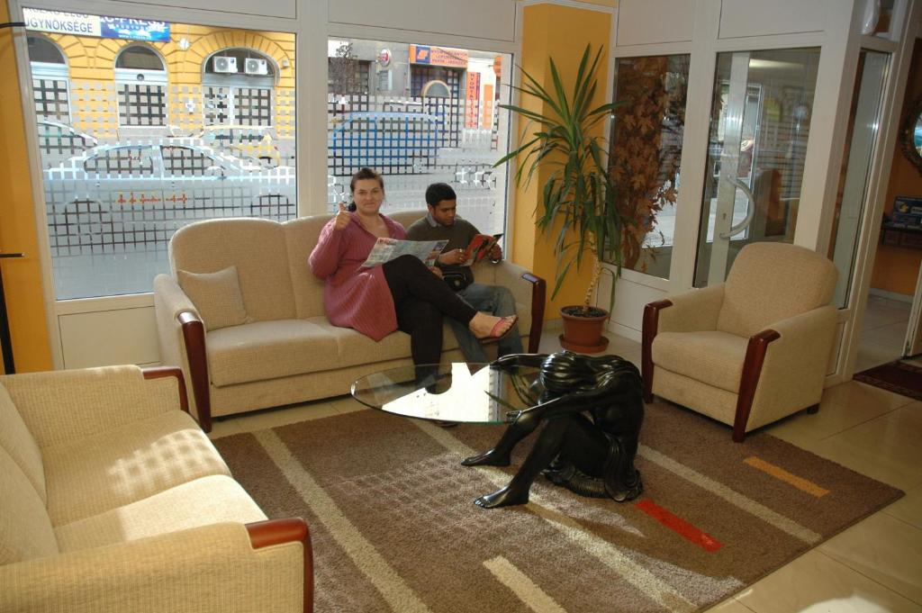twee mensen zitten op banken in een woonkamer met een hond bij Atlantic Hotel in Boedapest