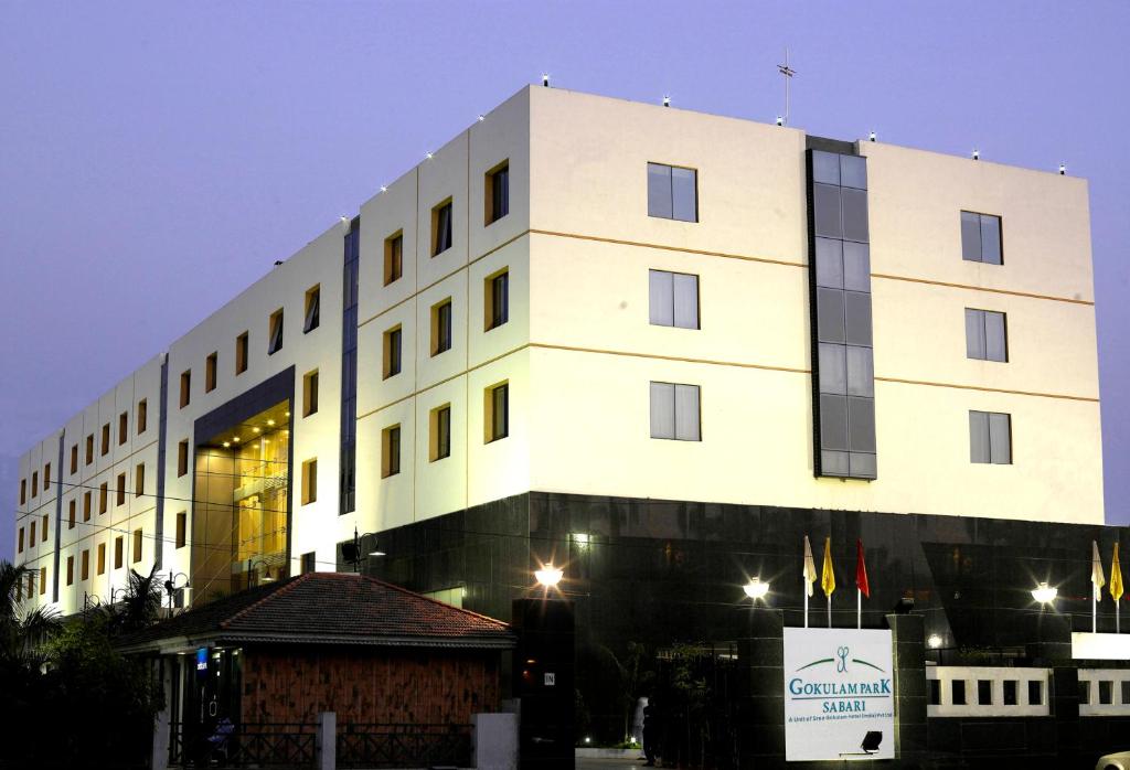 - un grand bâtiment blanc avec un panneau devant dans l'établissement Gokulam Park Sabari-Siruseri SIPCOT, à Chennai