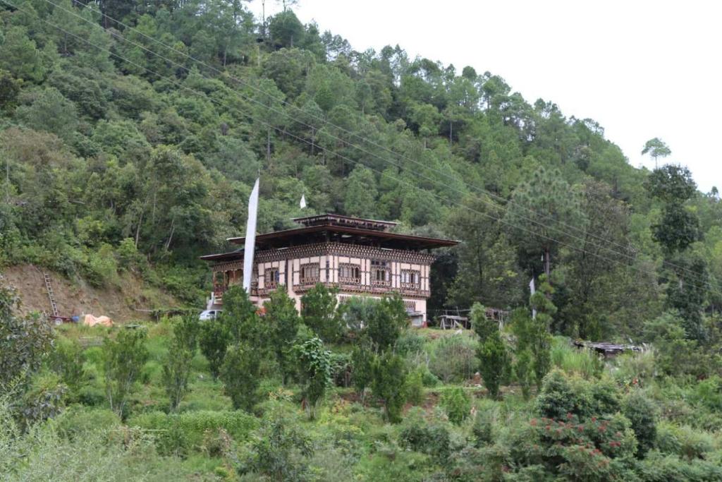 a house on the side of a hill in a field at Mendrelgang Homestay in Punākha