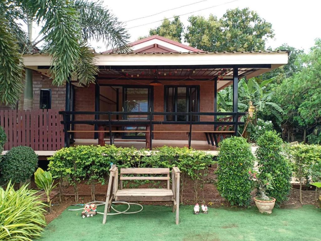 une petite maison avec un banc devant elle dans l'établissement โฮมสเตย์ ยายหนั่น, à Ban Nong Kham Tai