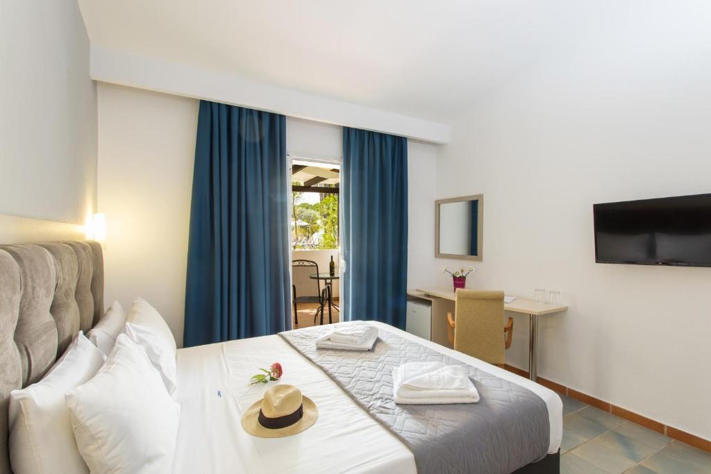 A bed or beds in a room at Coral Blue Beach Hotel Gerakini