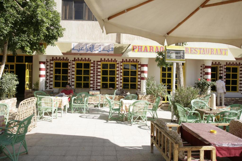 eine Außenterrasse mit Tischen und Stühlen sowie ein Restaurant in der Unterkunft Pharaohs Hotel in Luxor