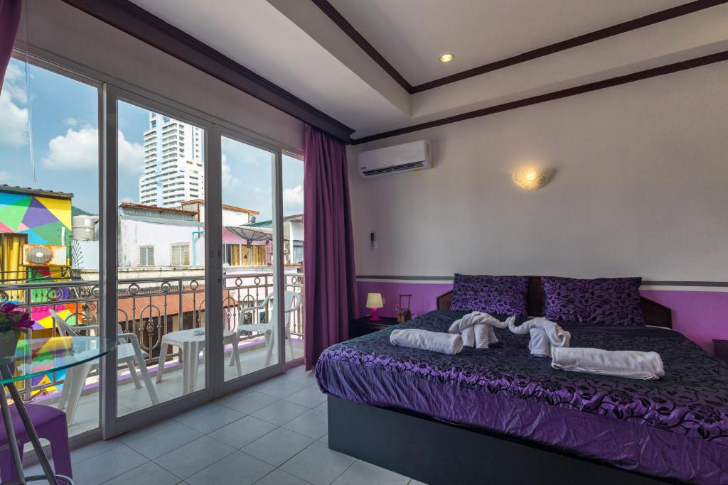 1 dormitorio con cama morada y balcón en Grand Orchid Inn Patong beach en Patong