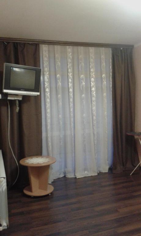 a living room with a curtain and a tv at Біля Драматичного театру in Ivano-Frankivsʼk