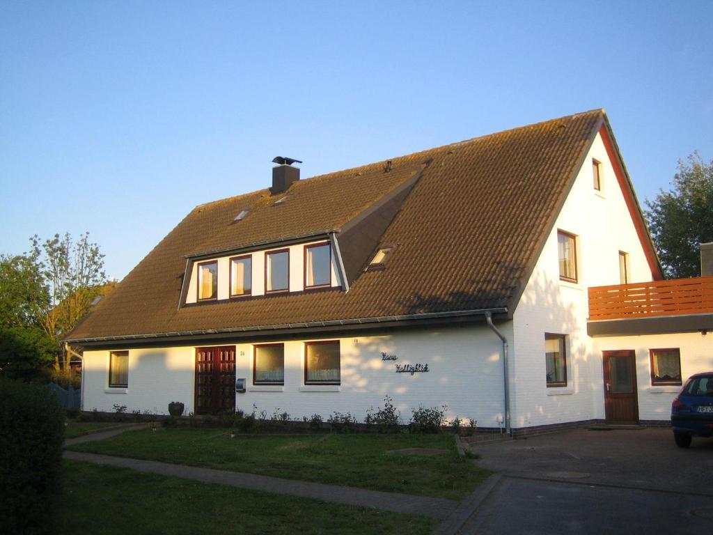 a white house with a brown roof at Haus-Halligblick-Ferienwohnung-Groede in Dagebüll