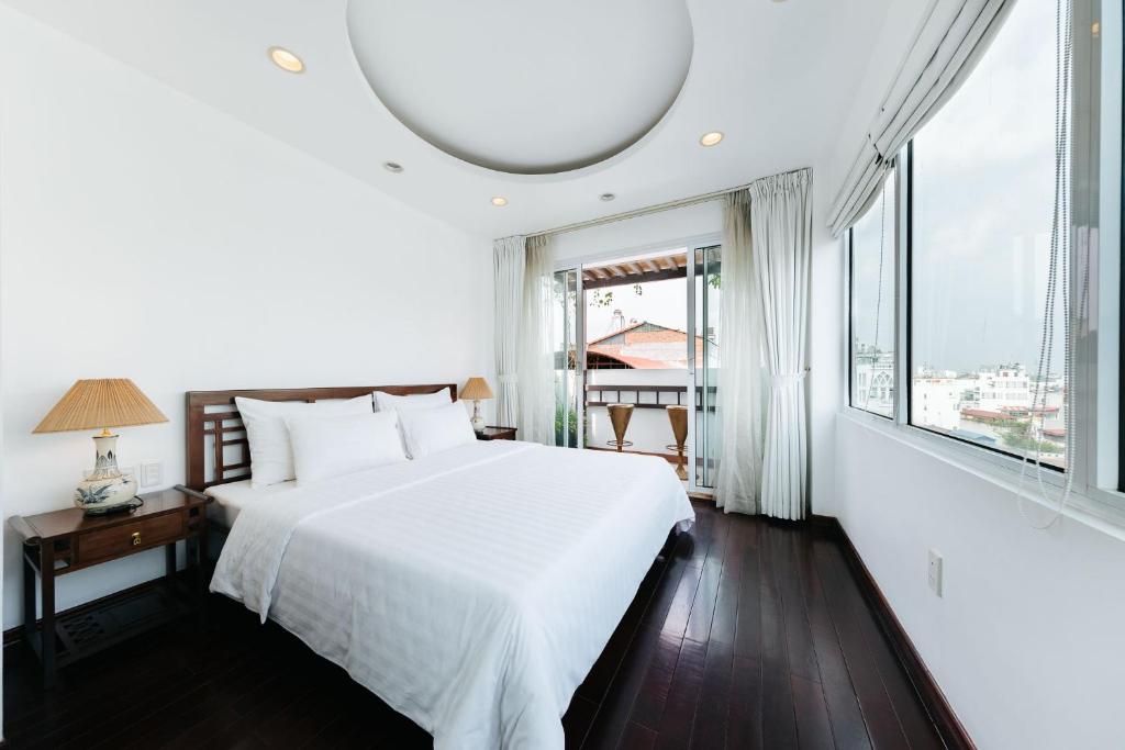 a bedroom with a white bed and a large window at VietHome-Doorstep to Hoan Kiem Lake in Hanoi