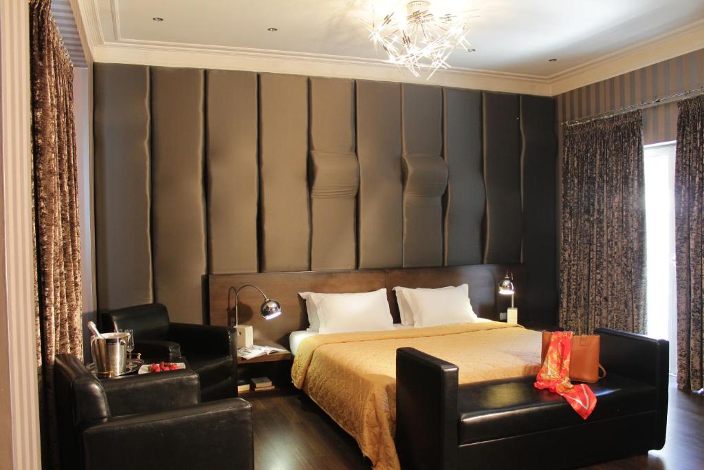 1 dormitorio con 1 cama y un par de sillas negras en Galaxy Art Hotel, en Oreokastro