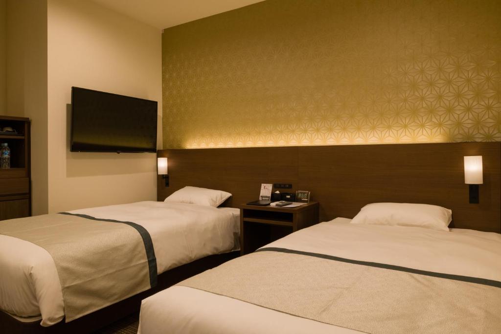 a hotel room with two beds and a flat screen tv at Tosei Hotel Cocone Ueno in Tokyo