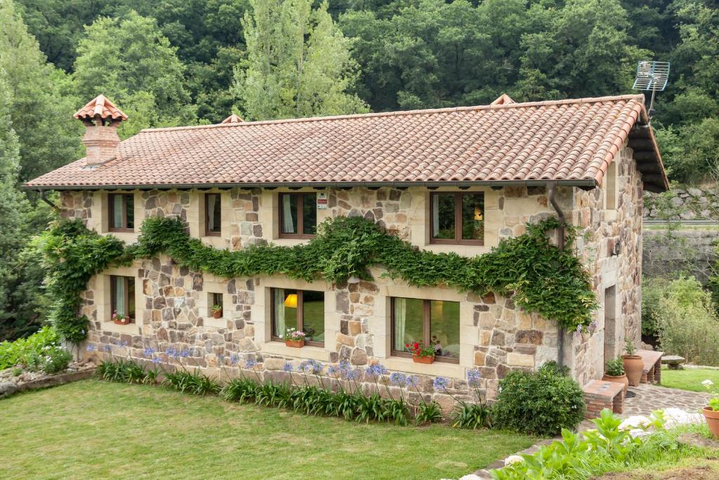 una casa de piedra con hiedra creciendo en ella en El Molino de Rucandio, en Liérganes