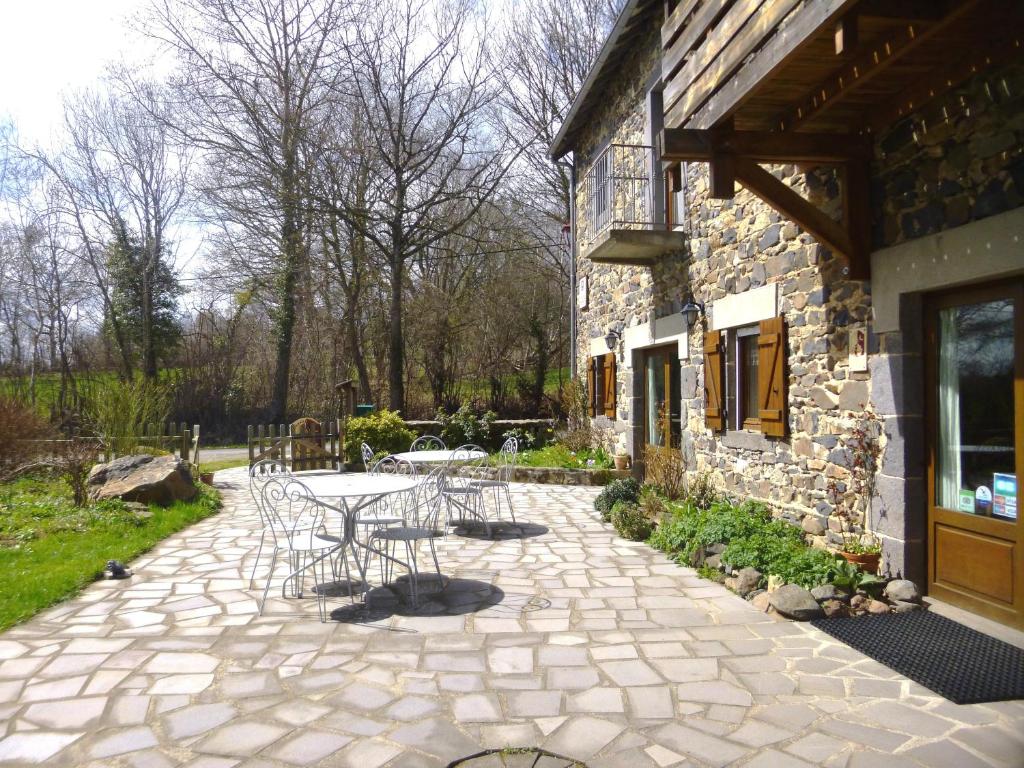 un patio con mesa y sillas junto a un edificio en Logis Hôtel Auberge de la Hulotte en Saint-Jacques-dʼAmbur