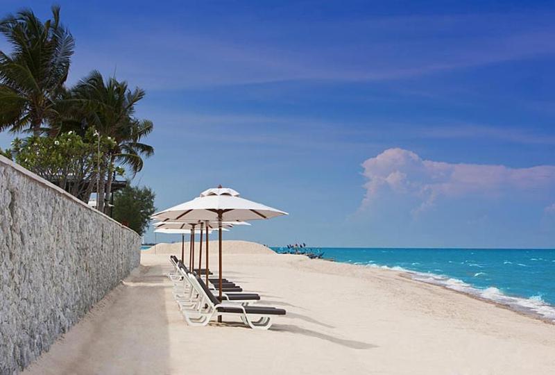 a beach with chairs and an umbrella and the ocean at Hua Hin Blue Lagoon in Cha Am