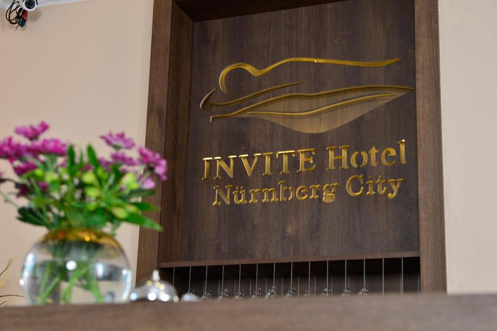 un cartel con un jarrón de flores en un estante en INVITE Hotel Nürnberg City, en Núremberg