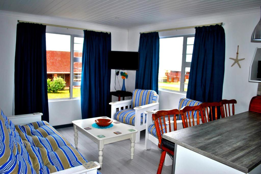 - un salon avec des rideaux bleus, une table et des chaises dans l'établissement Whale Watch Accommodation, à Gansbaai