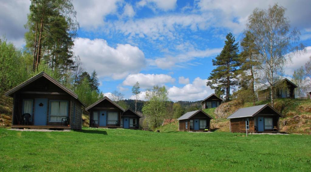 a group of cottages on a grassy hill at Mandalselva Laksehytter in Marnardal