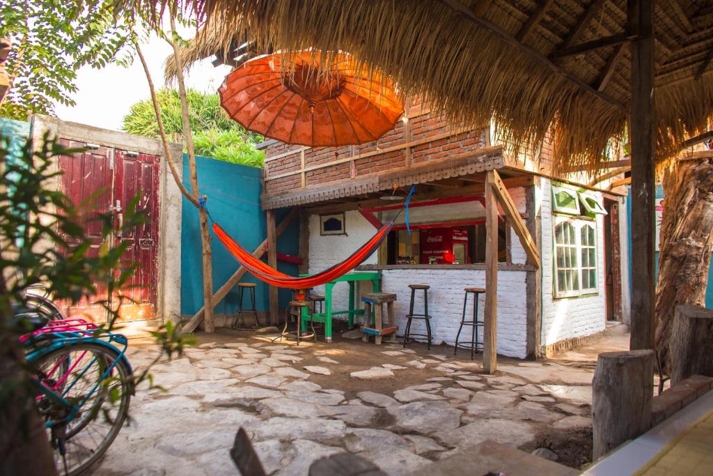 una casa con una sombrilla y una hamaca delante de ella en La Boheme Mini, en Gili Trawangan