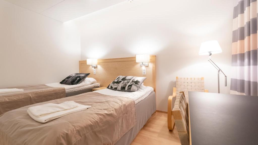 a small room with two beds and a lamp at Kokoushotelli Murikanranta in Terälahti