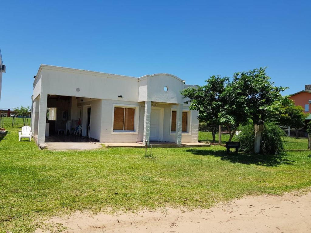 ein weißes Haus mit einem Baum im Hof in der Unterkunft Rancho Aparte in Ituzaingó