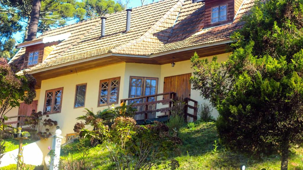 una casa amarilla en una colina con árboles en Chalé Suiço de Campos do Jordão, en Campos do Jordão