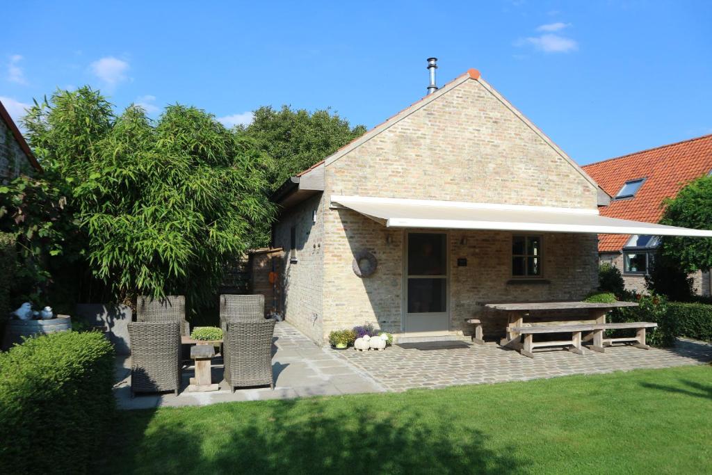 eine Terrasse mit einem Tisch, Stühlen und einer Bank in der Unterkunft Vakantiewoning 't Blooteland in Diksmuide