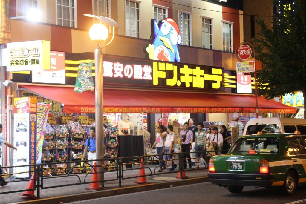 a street with people walking in front of a store at Shinjuku Welcome House inn in Tokyo