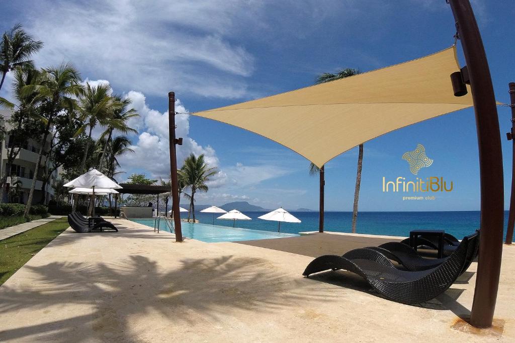 un complexe avec un grand parasol et une piscine dans l'établissement Instyle Residences at Infiniti Blu, à Sosúa