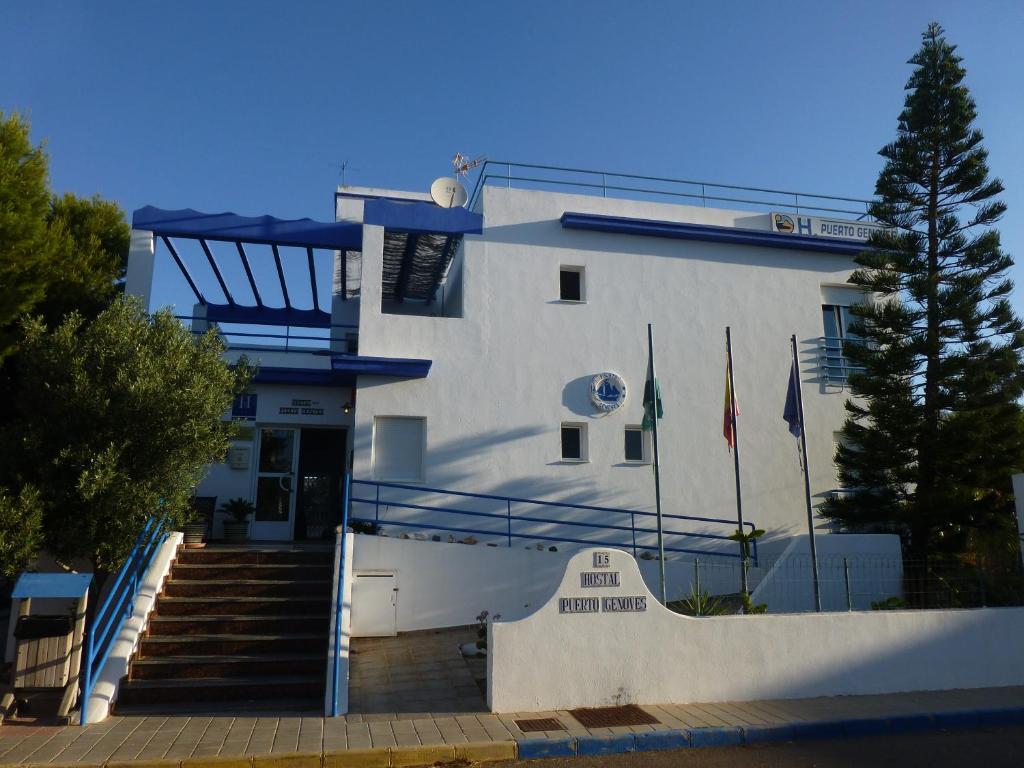 a large white building with a staircase in front of it at Hostal Puerto Genovés in San José